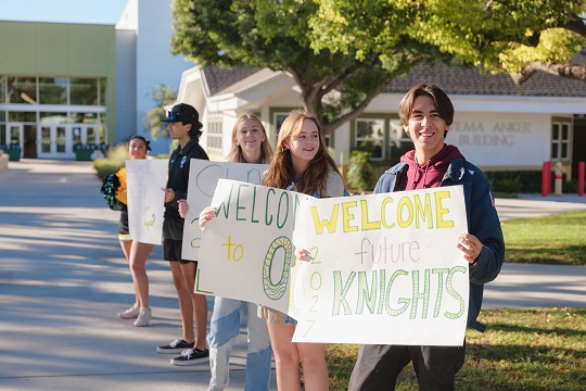 Knightline Magazine cover image of high school students holding signs that say "welcome future knights" to welcome 8th grade students and families to Knights Quest event