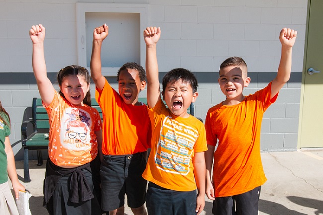 Four Elementary Students Wearing orange with fist in the air for Unity Day
