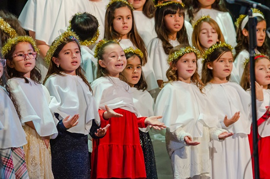 Elementary students dresses as angels singing with smiles at the Ontario Christian 1st though 4th grade Christmas program.