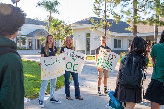 Three students holding welcome back signs on the first day of high school.