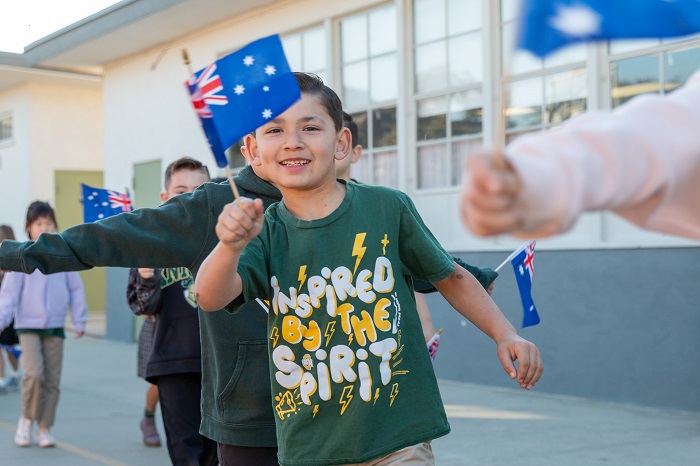 Elementary student waving Australian flag smiling at International Day.