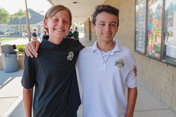 Two Ontario Christian male middle students hugging and smiling for a photo on campus.