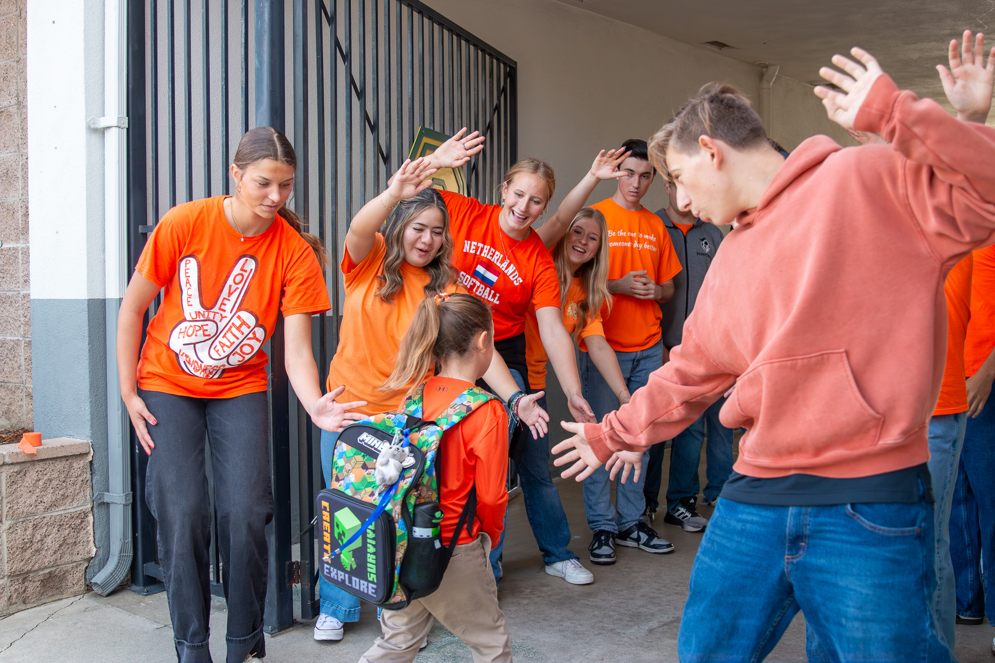 20251022UnityDay (1)-Enhanced-NR Three high school senior in their cap and gowns smiling at the crowd during the graduation ceremony.