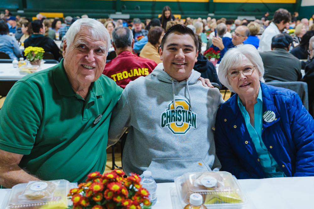 Three high school senior in their cap and gowns smiling at the crowd during the graduation ceremony.