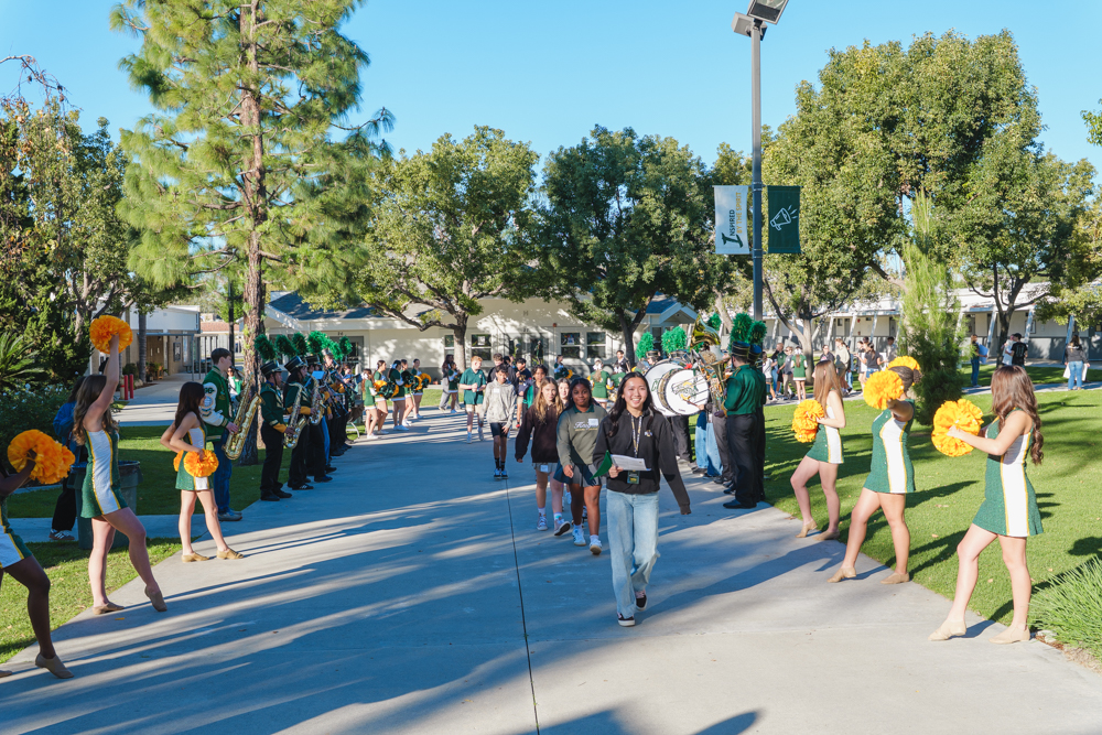 Three high school senior in their cap and gowns smiling at the crowd during the graduation ceremony.