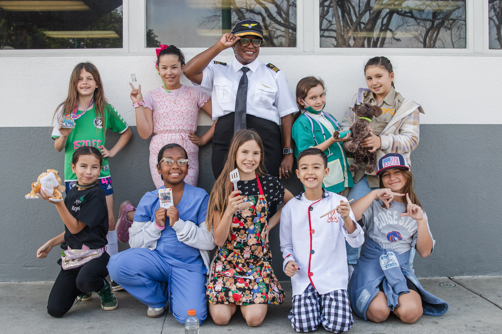Three high school senior in their cap and gowns smiling at the crowd during the graduation ceremony.