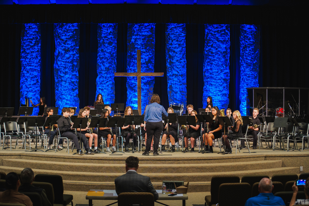 Three high school senior in their cap and gowns smiling at the crowd during the graduation ceremony.