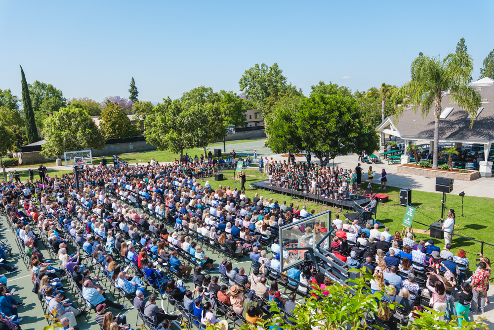 Three high school senior in their cap and gowns smiling at the crowd during the graduation ceremony.