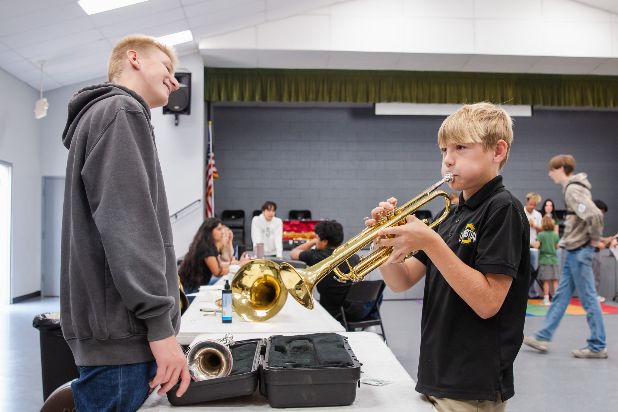 Three high school senior in their cap and gowns smiling at the crowd during the graduation ceremony.